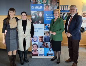 Madeline Garlick, Liliana Lyra Jubilut, Gillian Triggs, and James Milner posing in front of a UNHCR banner.