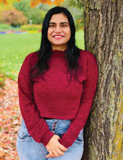 2020 Graduate Co-op Student of the Year Ritika Bhatia leaning against a tree against an autumnal landscape.