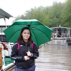 Undergraduate Co-op Student of the Year Claire DeJeu poses on a dock holding an umbrella in front of some boats.