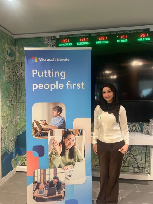 Farha Gomaa stands in front of a Microsoft Elevate banner at an event.