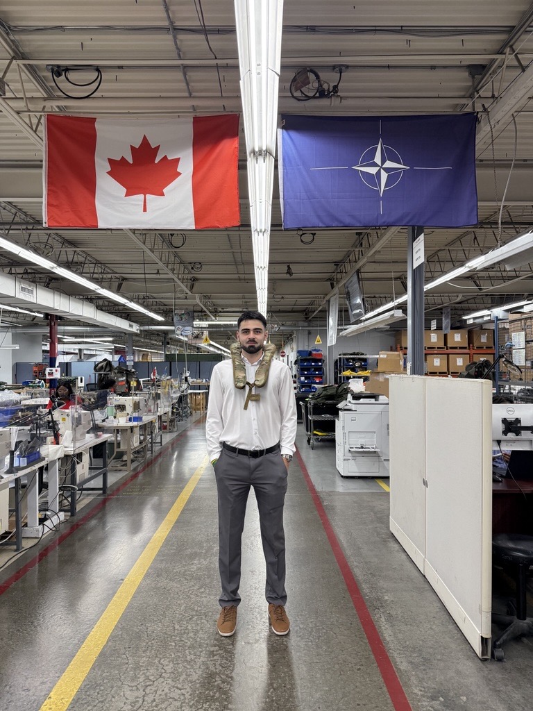 Alex stands in the Tulmar workshop area. He wears a Tulmar military life jacket.