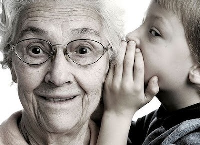 Boy whispering in grandma's ear