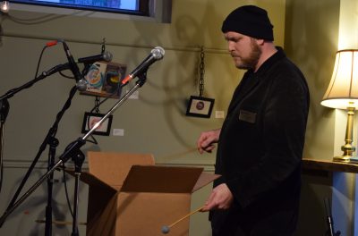 Jesse Stewart makes music using some cardboard boxes at ATEH's Building and Community with Homes for All event.