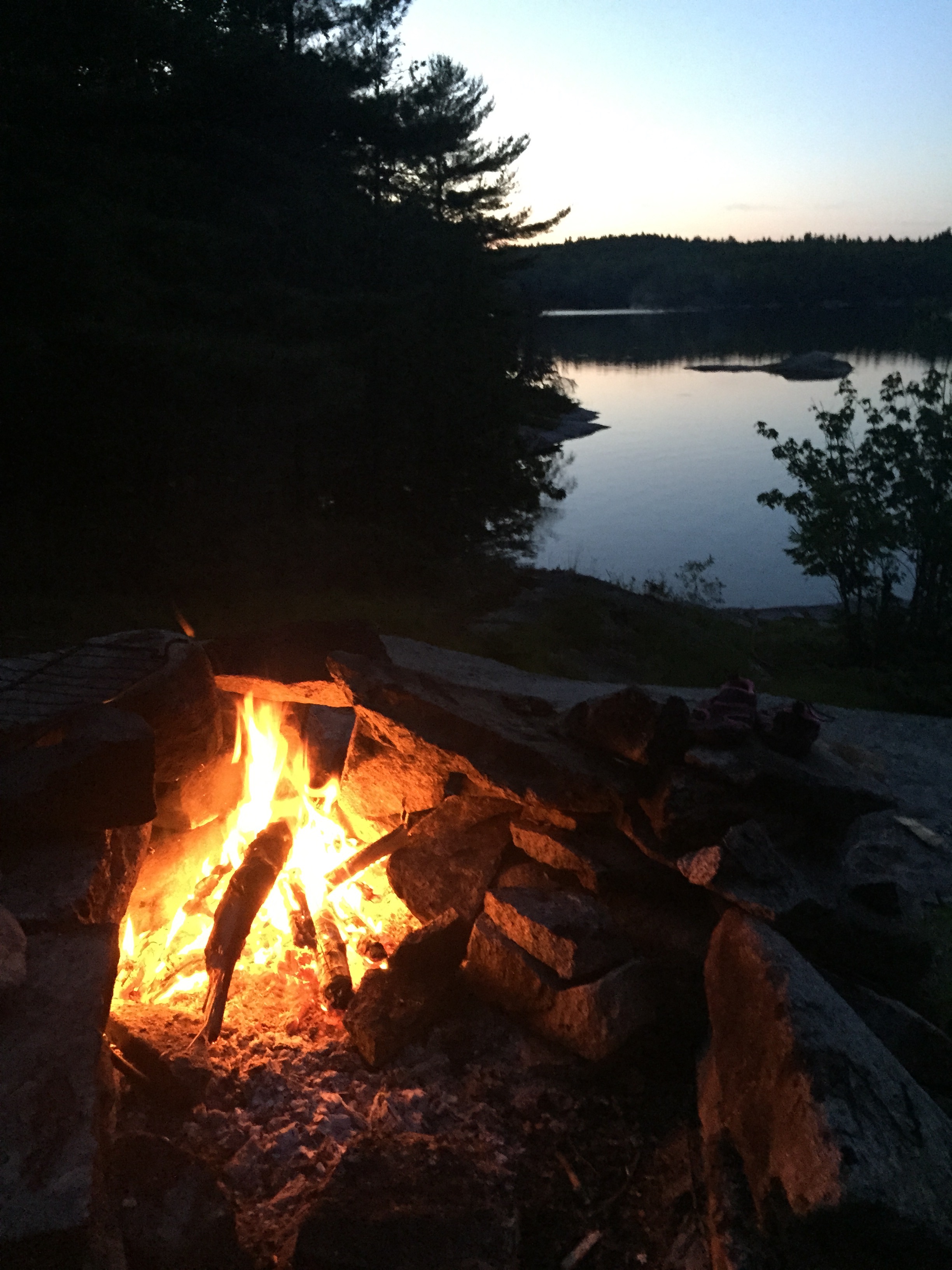 A campfire brightens up a camp sight along the water at Crotch Lake