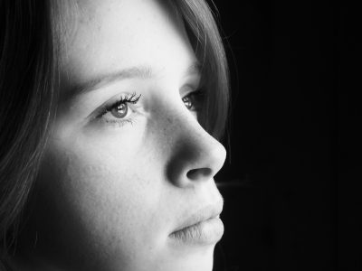 A close-up black and white photos of a young woman staring into the distance.