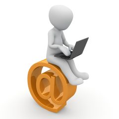 A human figure sits on top of an 'at' symbol with a laptop on its lap.