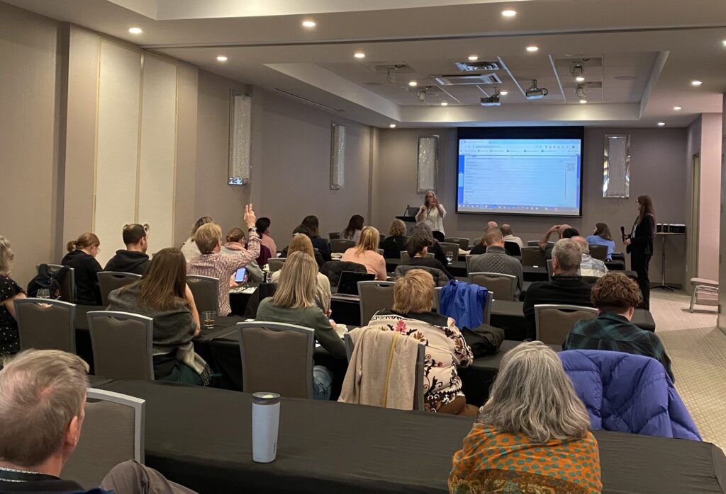 Dr. Kathleen Van Benthem standing in front of a group of workshop participants, speaking and gesturing.