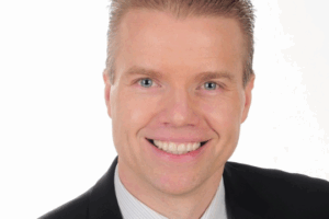 Headshot of Daniel Gulanowski. He is wearing a black suit with a white dress shirt and blue-striped tie.