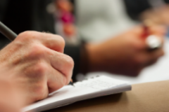 Close up of hand taking notes during a meeting with other people