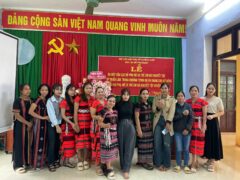 A group of girls and women standing, some of them wearing their traditional brocade costumes.