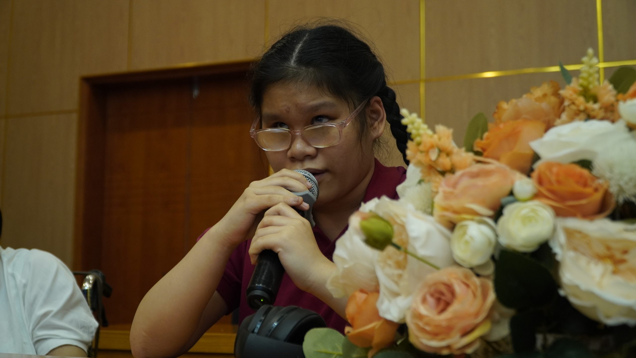 A girl with braids is wearing a red shirt and holding a microphone