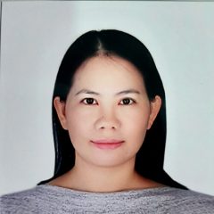 This is a portrait of a woman with long black hair. She is wearing a grey shirt. 