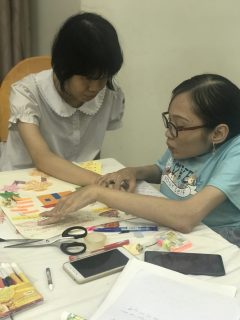 A woman is holding a girl's hand to support describe the drawing.