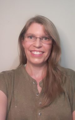 This is a portrait of a woman with straight long blond hair. She is wearing a greenshirt.