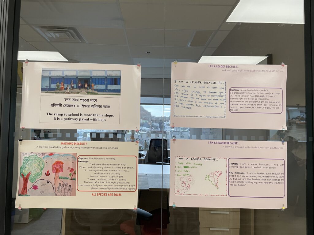 Four posters displayed on a glass wall.