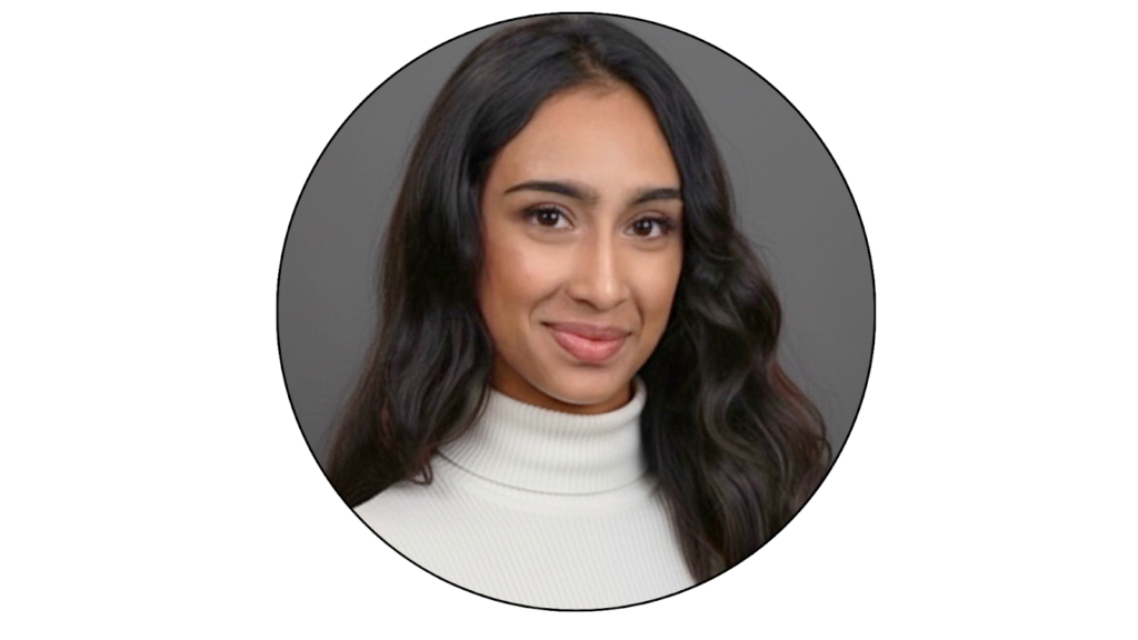 A person with long hair hair wearing a light-coloured turtleneck, smiling against a natural background.