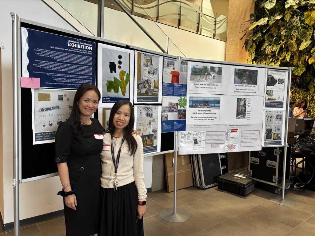 Two people standing in front of two large boards displaying different collages, drawings, and photovoice artworks.