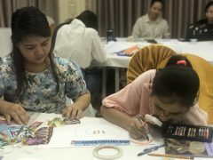 There are a girl and a woman working on their art-works.