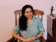 This is a photo of a woman with long wavy, black hair who wearing a blue dress.