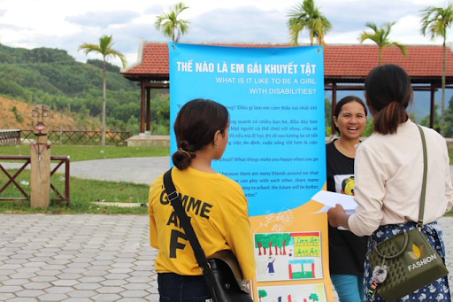 The two girls and one woman have a presentation to community members.