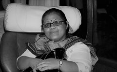 There is a black and white portrait of a woman wearing glasses. She is wearing a patterned scarf and a white shirt.