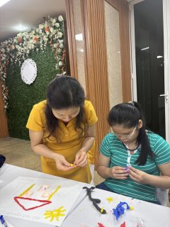 A woman and a girl are decorating their artwork.