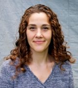 Women with auburn hair, smiling and wearing a blue/grey sweater. 