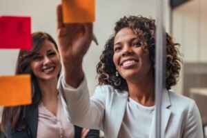 Two women standing in front of post-it notes attached to a glass wall