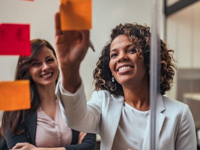 Two women standing in front of post-it notes attached to a glass wall