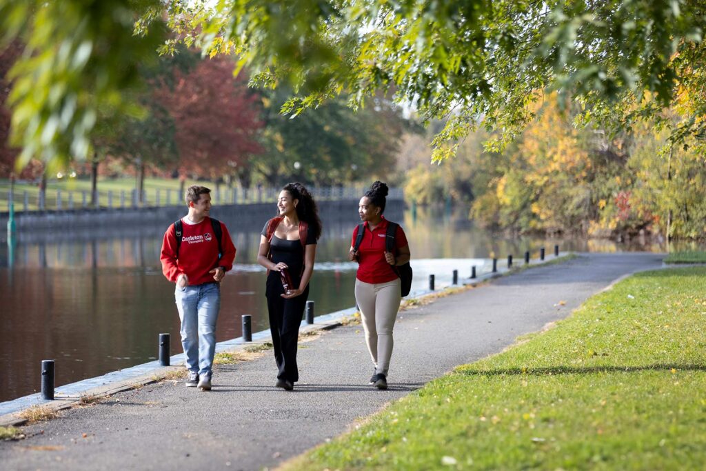 Three young people walking together on a bike bath, alongside a canal.