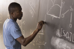 student writing on whiteboard with formulas on it