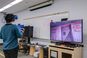 Student standing in front of screen with VR set on