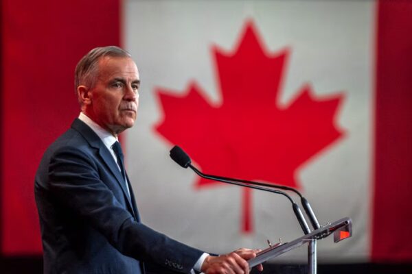 Pm Mark Carney infront of a Canadian flag