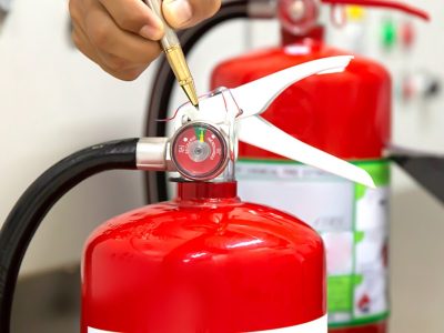 Individual pointing at fire extinguisher gauge with pen