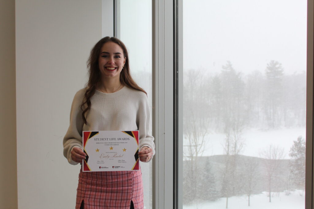 Emily Knobel holding the Adrian Chan award certificate. 