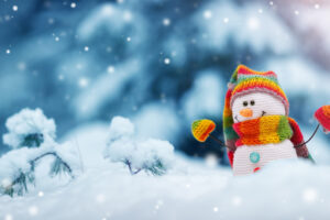 little snowman on soft snow on blue background