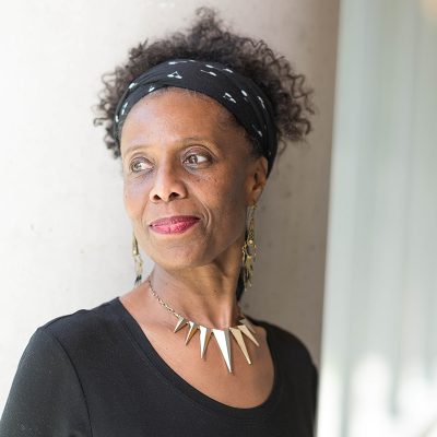 A Black Woman wearing a black shirt and black headband looks away from the camera