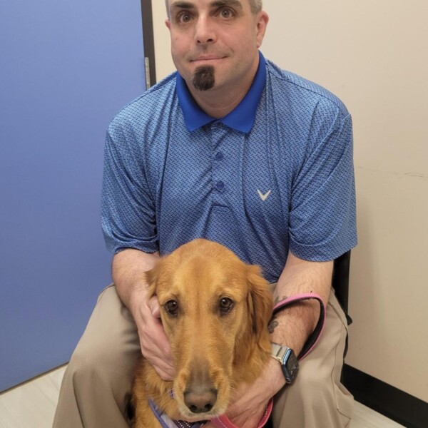 Photo of smiling student employee Anthony and his service dog, Angel.