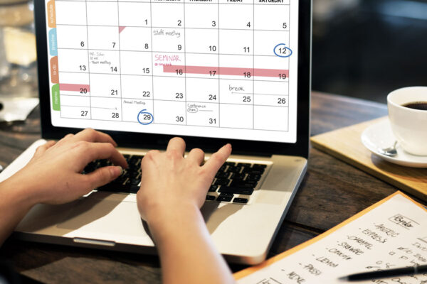 Woman typing on computer, looking at calendar on screen