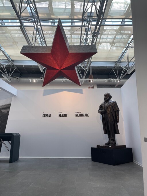 Interior of Museum of Communism, Prague, Czechia, with red star hanging from ceiling and statue of Karl Marx.