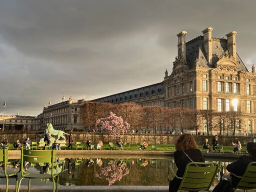 Jardin de Tuileries Paris - Louvre castle with pond and people sitting around it.