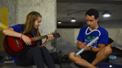 Two students playing some music while taking a break from raft building.