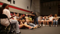 Hypnotist on stage with a bunch of students seated and asleep.