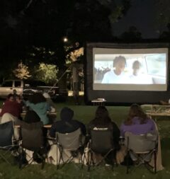 students watching a movie on outdoor screen.