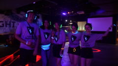Students wearing ravens shirts that glow in the dark while holding neon glow headphones at a dance.