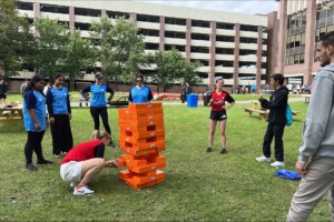Students playing giant jenga on grass.