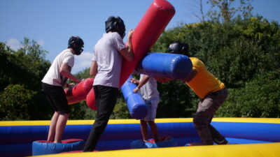 Students playing on a large joust game outdoors.