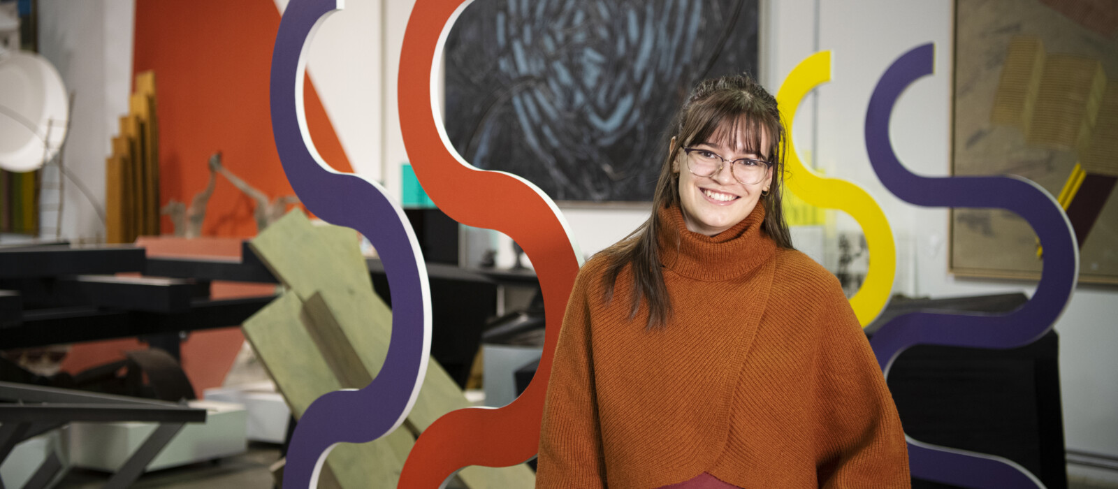 a student posing amidst art work