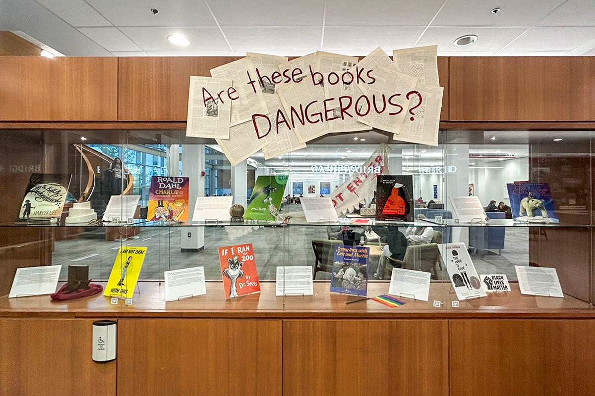 A display behind glass at the Carleton library featuring banned books and a banner that reads "Are These Books Dangerous?"