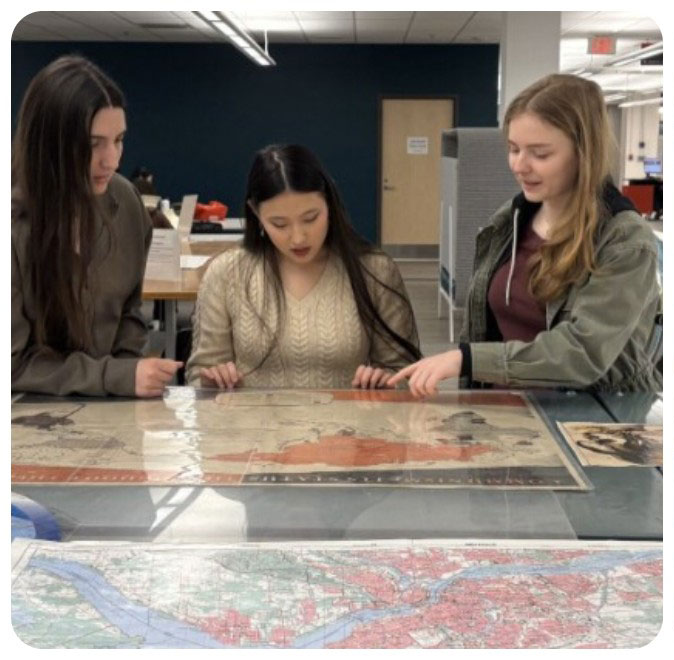 On the far left, first-year students, Arabella Skliar (left), Carys Murray (middle), and Maria Coates (right) evaluate a 1950 communist map, which they subsequently compare to a propaganda map from the late 1800s. Photographs by Emme Reynolds and Sherri Sunstrum.
